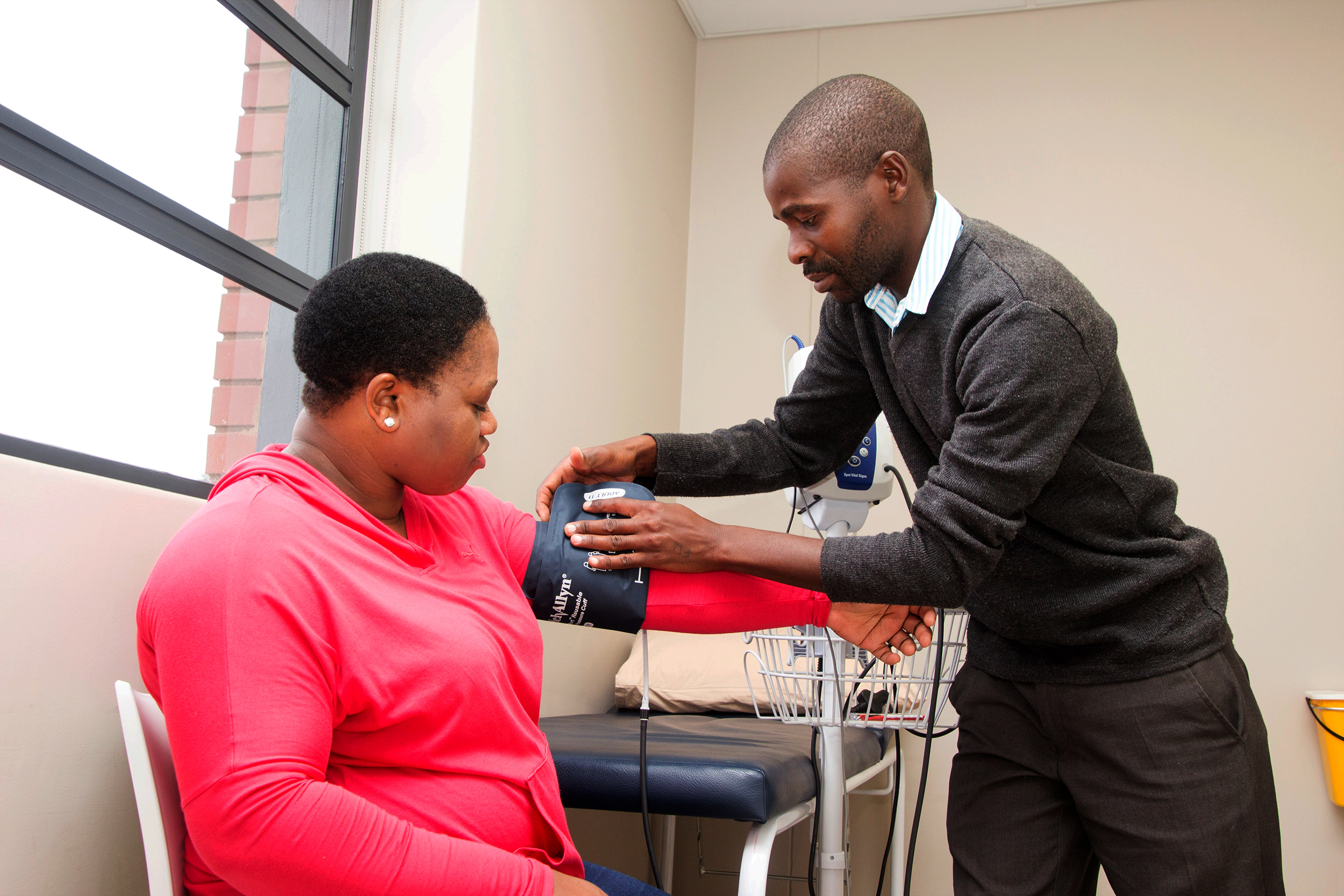 A man taking a woman's blood pressure